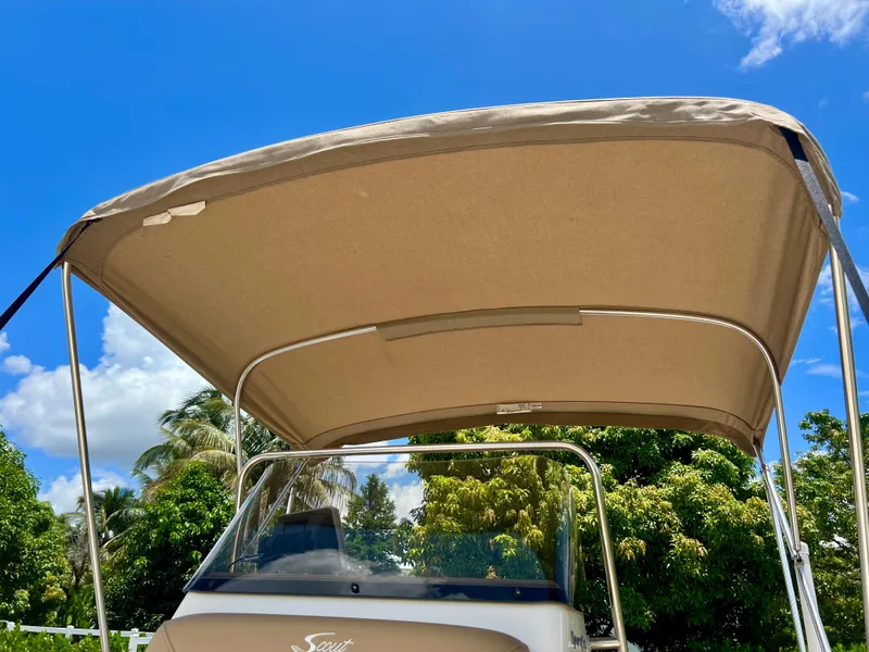 Slide: The Image of 2019 Scout Sportfish 175 boat with bimini top under clear blue sky. - 10