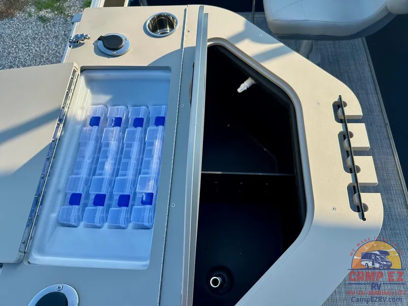 Slide: The Image of 2025 South Bay 224FCR LE boat storage compartment with tackle boxes and cup holder. - 20