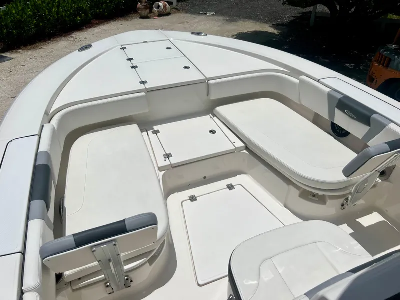 Slide: The Image of 2022 Robalo 266 Cayman boat interior with white cushioned seating and storage compartments. - 12