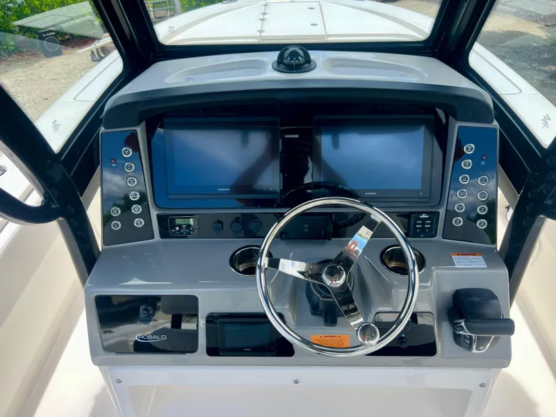 Slide: The Image of 2022 Robalo 266 Cayman boat dashboard with dual screens and steering wheel. - 17