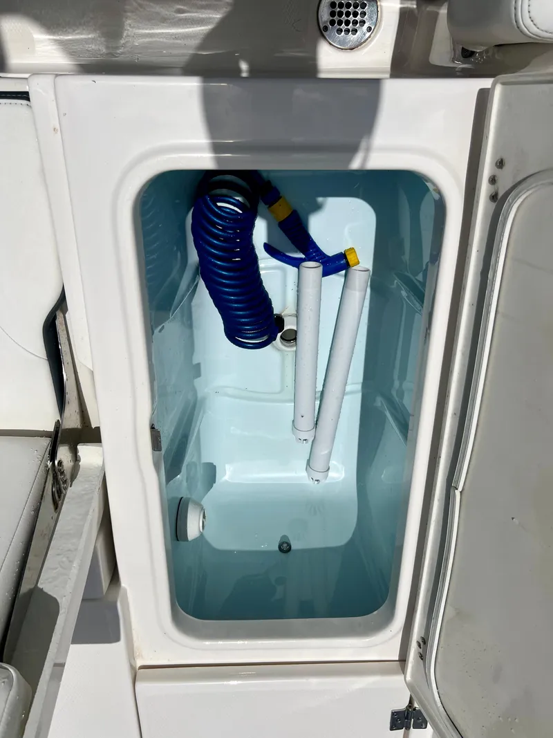 Slide: The Image of 2022 Robalo 266 Cayman storage compartment with coiled hose and accessories. - 21