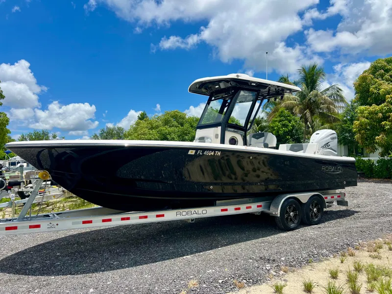 Slide: The Image of 2022 Robalo 266 Cayman boat on a trailer, parked outdoors under a blue sky. - 3