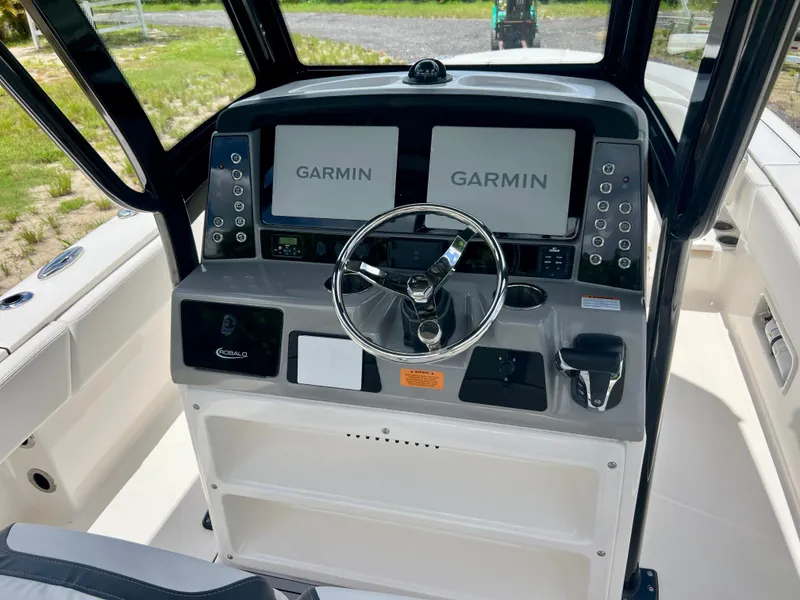 Slide: The Image of 2022 Robalo 266 Cayman boat dashboard with dual Garmin displays and steering wheel. - 30