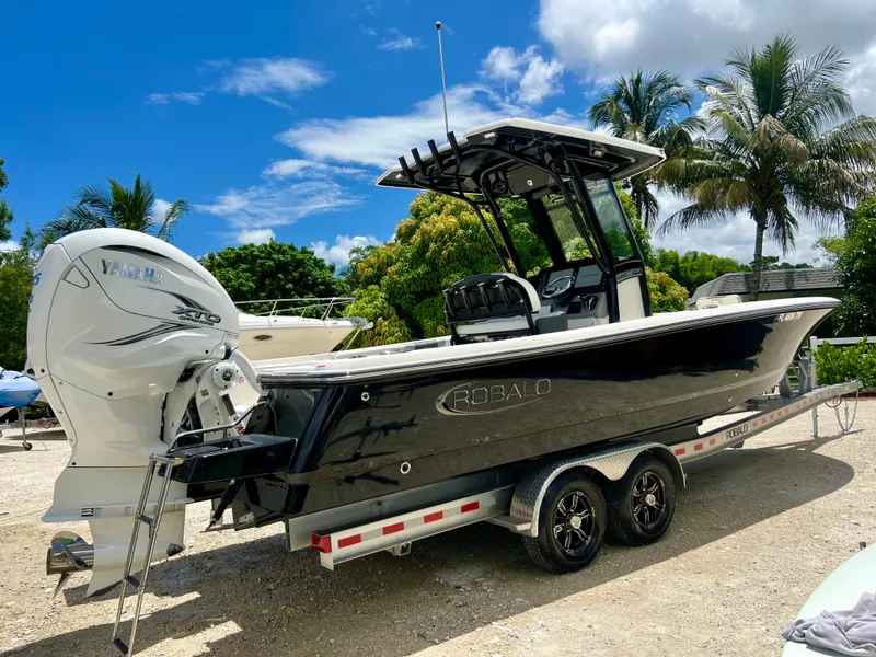 Slide: The Image of 2022 Robalo 266 Cayman boat on a trailer, parked outdoors under a clear blue sky. - 37