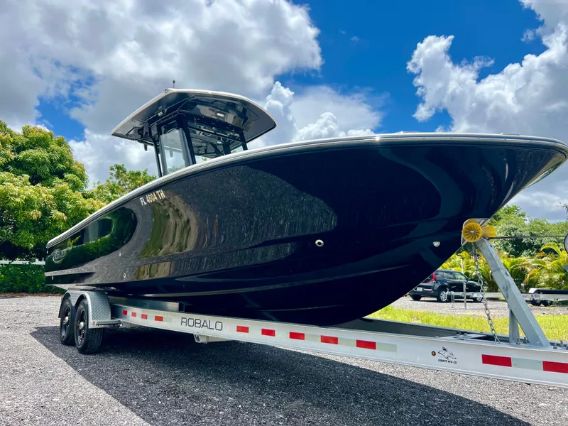 Slide: The Image of 2022 Robalo 266 Cayman boat on a trailer under a blue sky. - 4