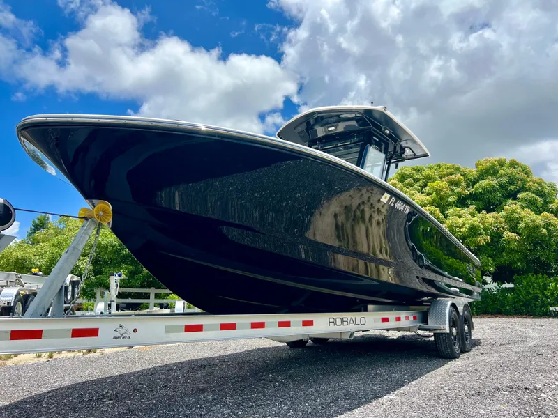 Slide: The Image of 2022 Robalo 266 Cayman boat on a trailer under a blue sky with clouds. - 7