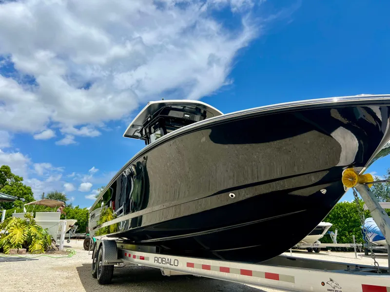 Slide: The Image of 2022 Robalo 266 Cayman boat on a trailer under a blue sky. - 8