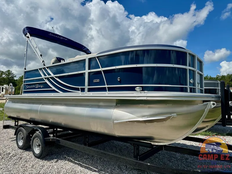 The Image of 2025 South Bay 220CR LE pontoon boat on a trailer under a cloudy sky. - 0