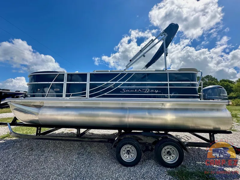 Slide: The Image of 2025 South Bay 220CR LE pontoon boat on a trailer under a blue sky. - 3