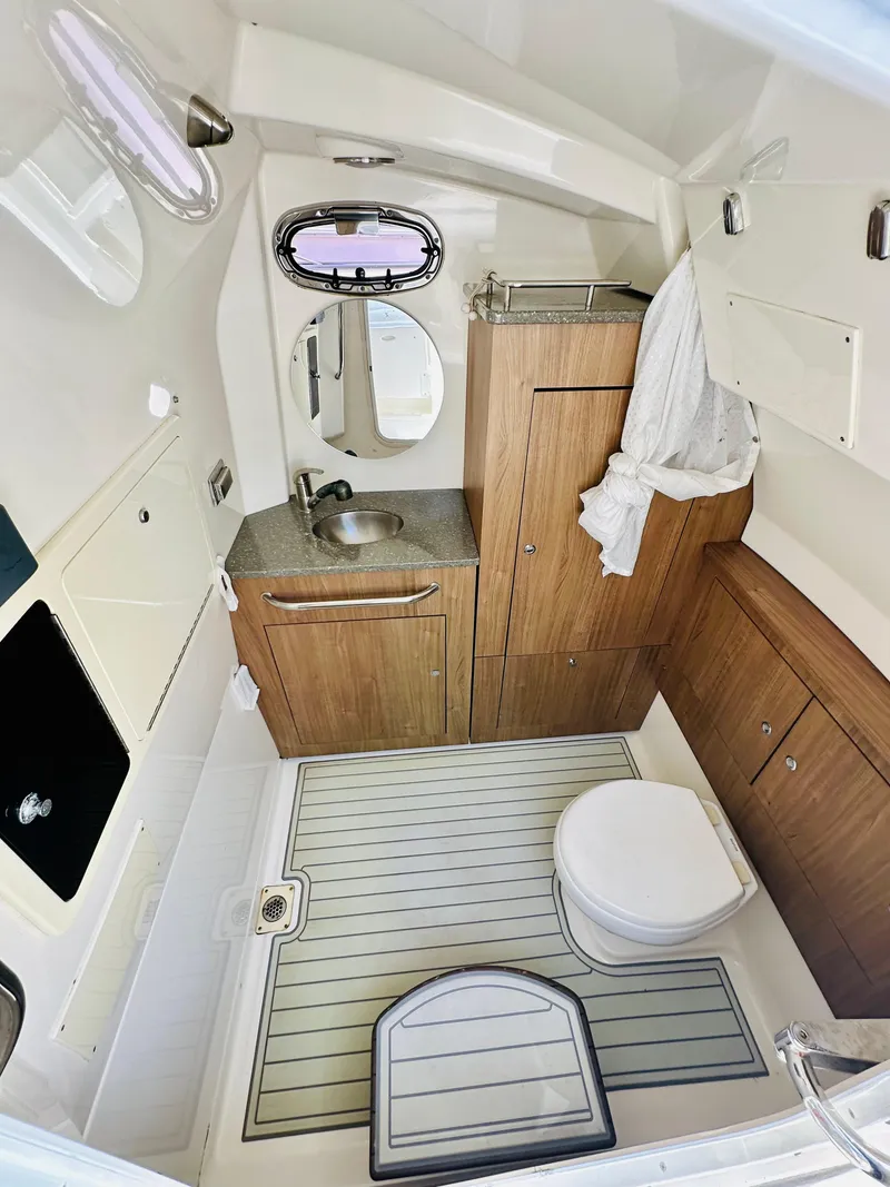 Slide: The Image of 2016 Boston Whaler 350 Outrage cabin interior with sink, toilet, and wooden cabinetry. - 10