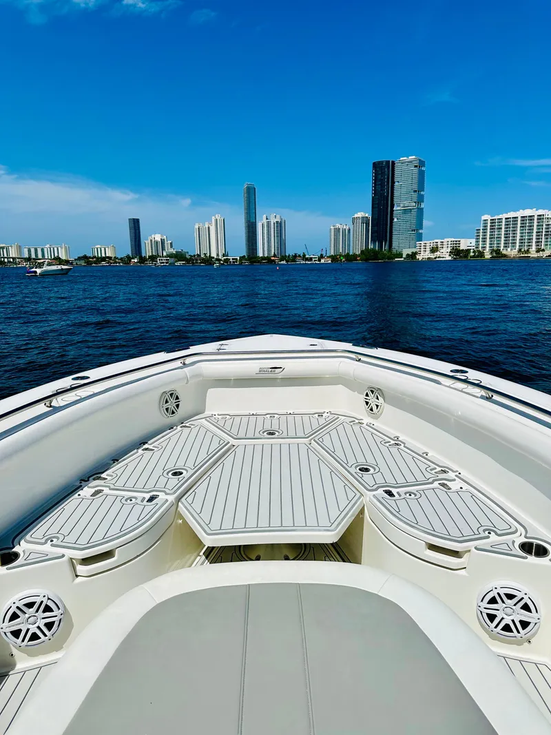 Slide: The Image of 2016 Boston Whaler 350 Outrage boat cruising with city skyline in background. - 16