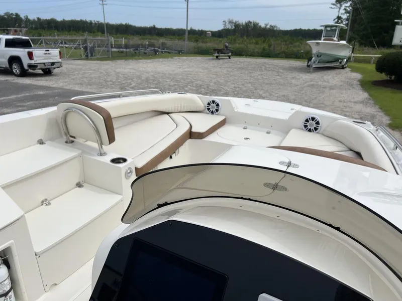 Slide: The Image of 2024 Stingray 212SC boat interior with seating and dashboard, parked on gravel lot. - 9