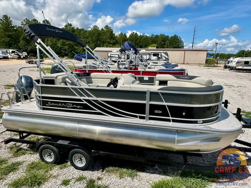 The Image of 2025 South Bay 220CR LE pontoon boat on a trailer in a dealership lot. - 1