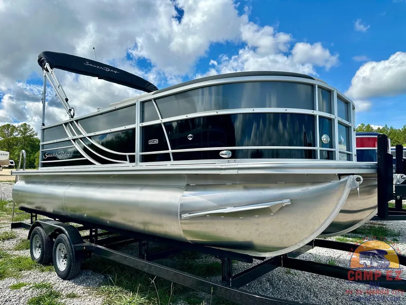 Slide: The Image of 2025 South Bay 220CR LE pontoon boat on a trailer under a partly cloudy sky. - 3
