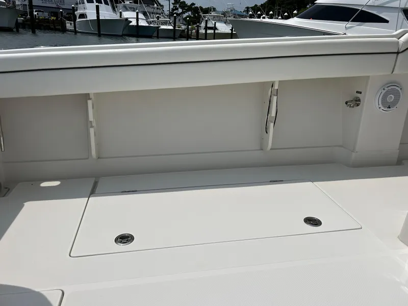 Slide: The Image of 2016 Jupiter 34 HFS boat deck with storage compartments and docked yachts in the background. - 35