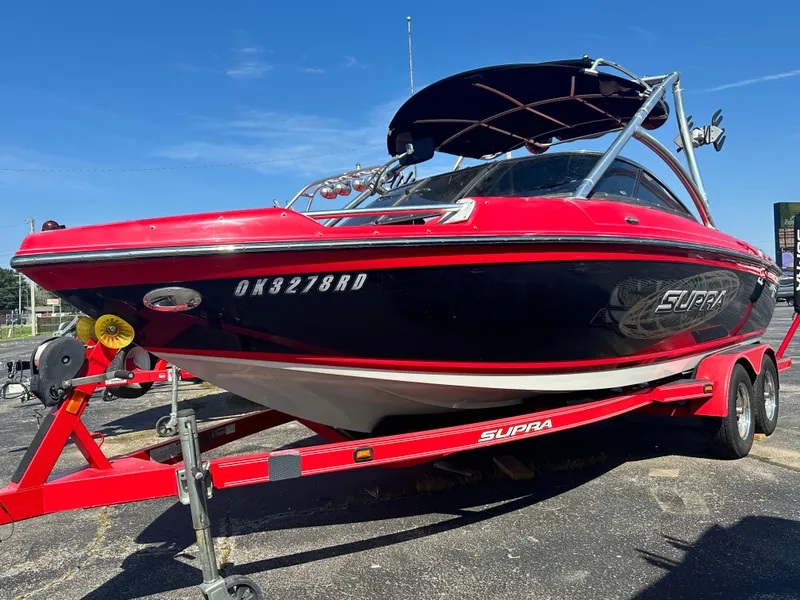 Slide: The Image of 2009 Supra 21V LAUNCH boat on a red trailer under a clear blue sky. - 3