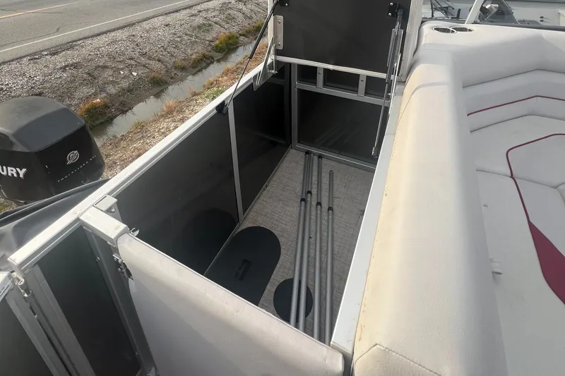Slide: The Image of 2022 SunCatcher Select 18C boat interior storage compartment with seating and Mercury outboard motor. - 16