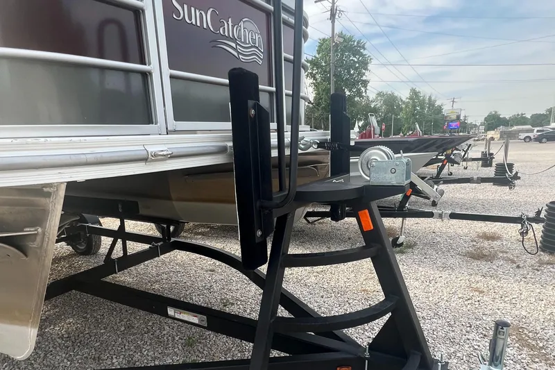 Slide: The Image of 2022 SunCatcher Select 18C pontoon boat on a trailer in a gravel lot. - 8