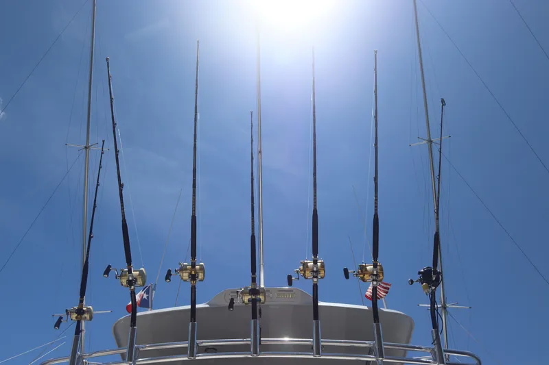 Slide: The Image of Fishing rods on a 2003 Hatteras 70 Convertible yacht under a bright sun. - 12
