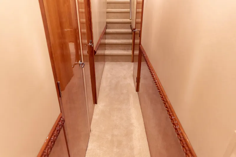 Slide: The Image of Hallway inside 2003 Hatteras 70 Convertible yacht with carpeted stairs and wooden doors. - 27