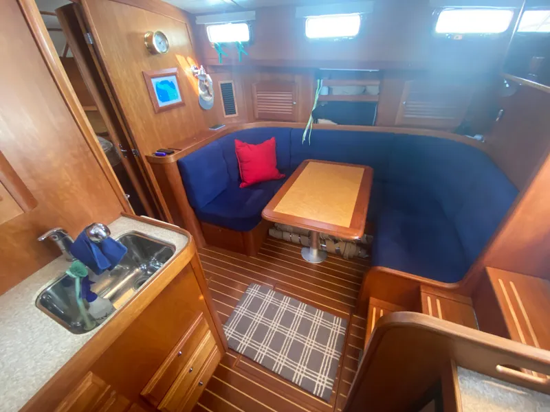 Slide: The Image of Interior of 2003 Sabre 36 sailboat with blue seating, wooden table, and kitchenette. - 4