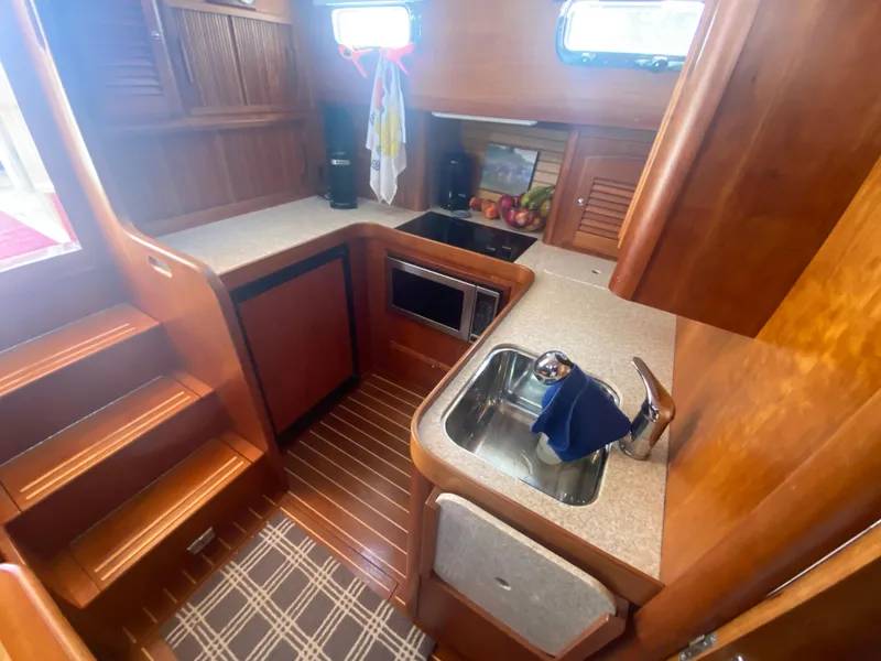 Slide: The Image of 2003 Sabre 36 yacht kitchen with wooden cabinetry, sink, microwave, and countertop. - 8
