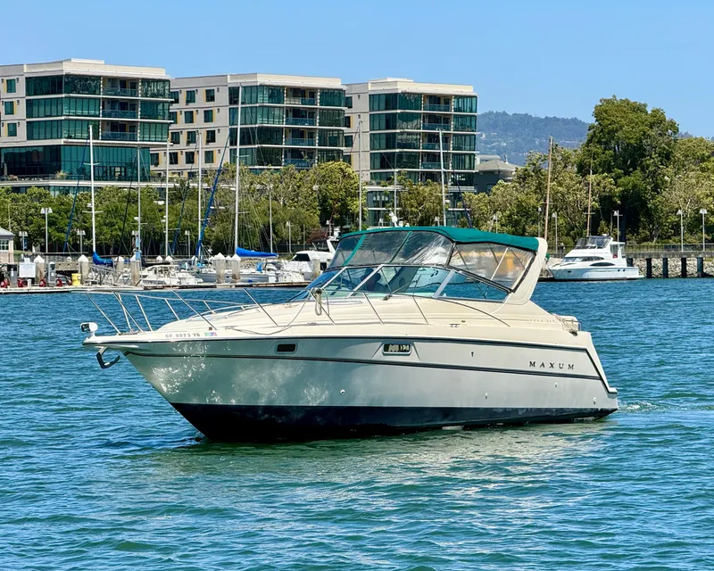 Slide: The Image of 1997 Maxum 3200 SCR boat cruising near modern waterfront buildings. - 0