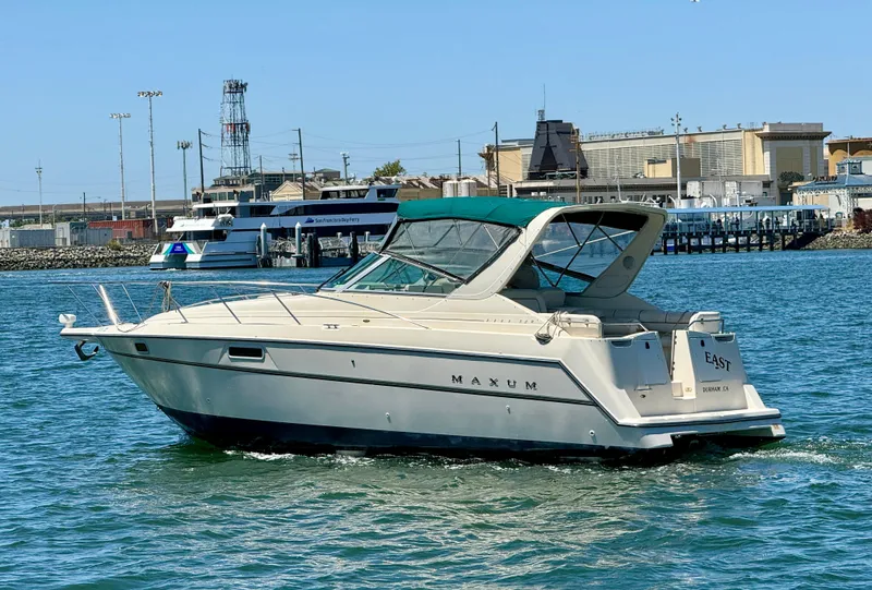 Slide: The Image of 1997 Maxum 3200 SCR boat cruising in a harbor with industrial background. - 1
