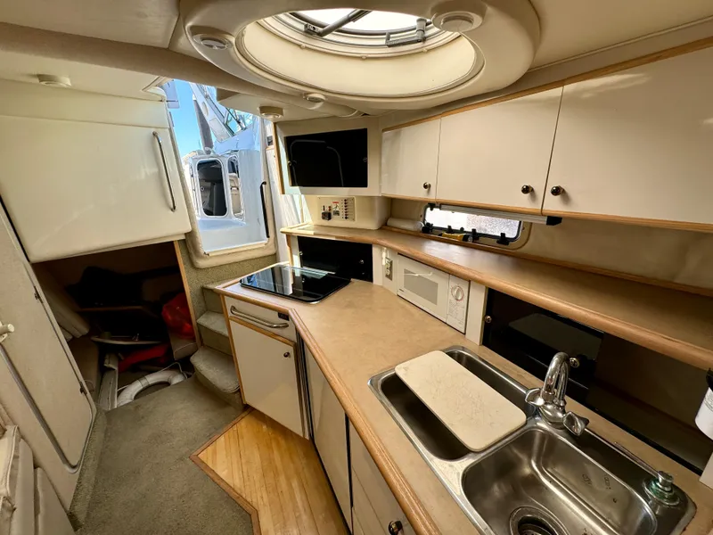 Slide: The Image of 1997 Maxum 3200 SCR boat interior with kitchenette, sink, and storage cabinets. - 10