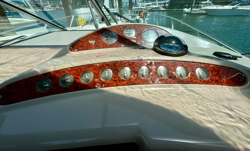 Slide: The Image of 1997 Maxum 3200 SCR boat dashboard with wood paneling and gauges, docked at marina. - 14