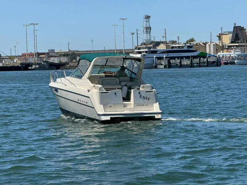 Slide: The Image of 1997 Maxum 3200 SCR boat cruising in a harbor with cityscape background. - 2