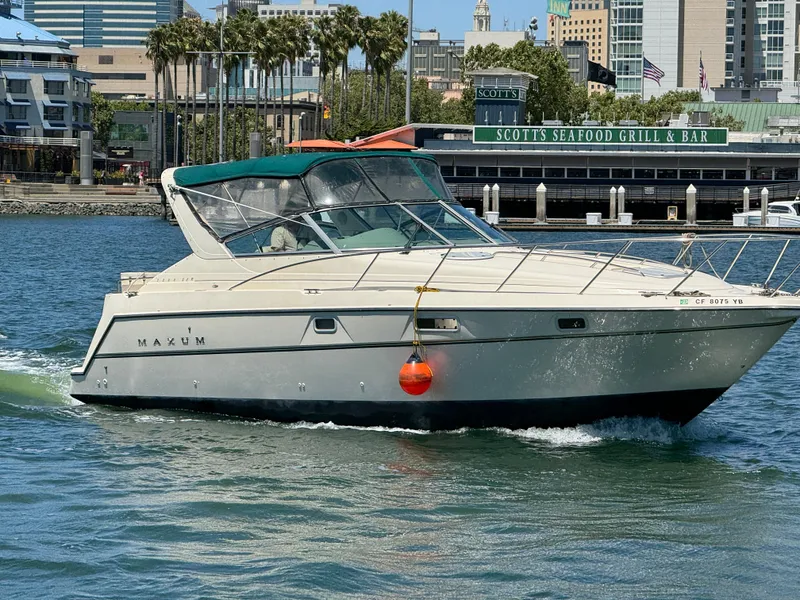 Slide: The Image of 1997 Maxum 3200 SCR boat cruising near waterfront restaurant, sunny day. - 3