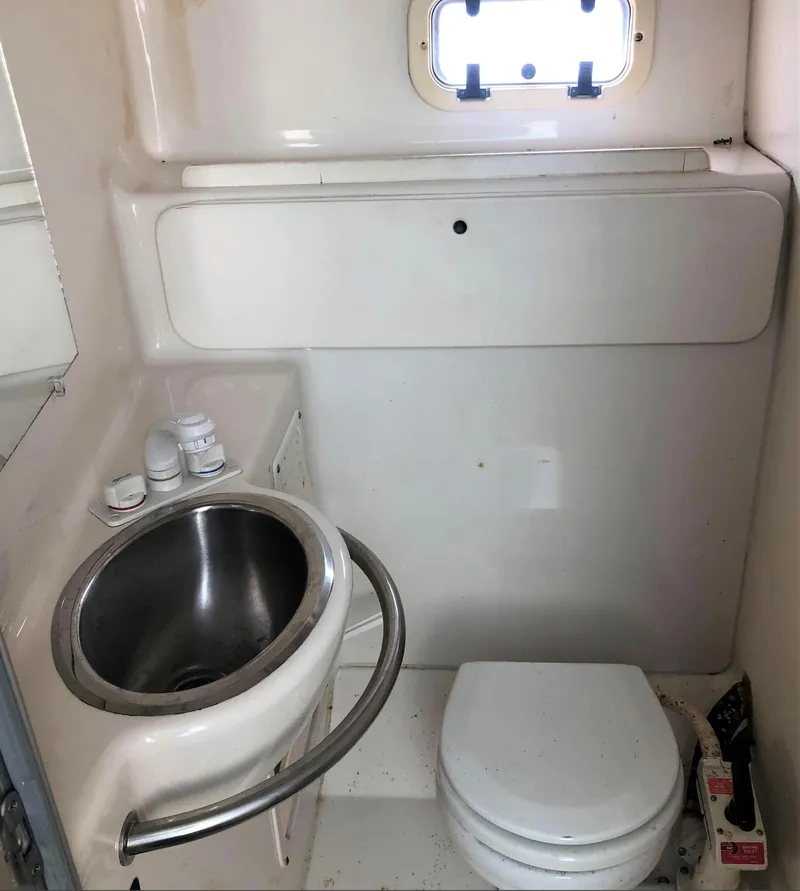 Slide: The Image of 1997 Maxum 3200 SCR boat bathroom with sink, toilet, and small window. - 8