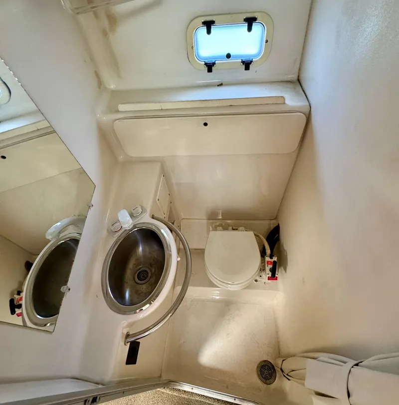 Slide: The Image of 1997 Maxum 3200 SCR boat bathroom with sink, toilet, and porthole window. - 9