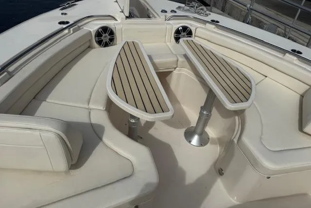 Slide: The Image of 2024 Grady-White Canyon 456 boat interior with cushioned seating and wooden tables. - 12