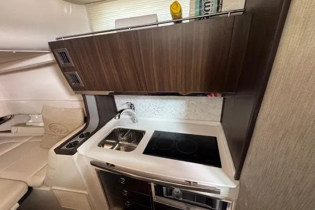 Slide: The Image of 2024 Grady-White Canyon 456 interior kitchen with sink, stove, and wooden cabinetry. - 37