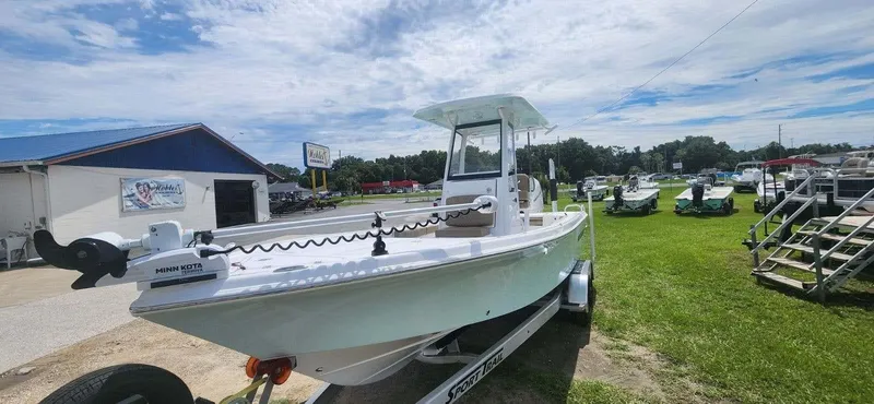Slide: The Image of 2025 Blazer Bay 2440 boat on trailer at dealership under a partly cloudy sky. - 2