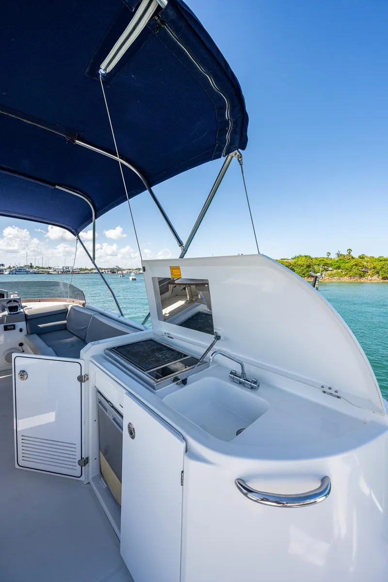 Slide: The Image of 2018 Beneteau Swift Trawler 44 flybridge with seating and table, overlooking a harbor. - 13