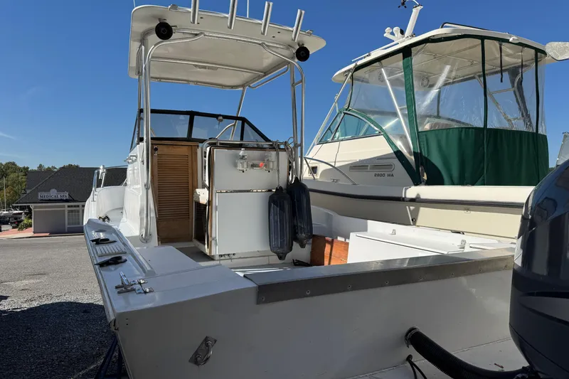 Slide: The Image of 1981 Mako 233 Walk Around boat with open deck and canopy, parked outdoors. - 1