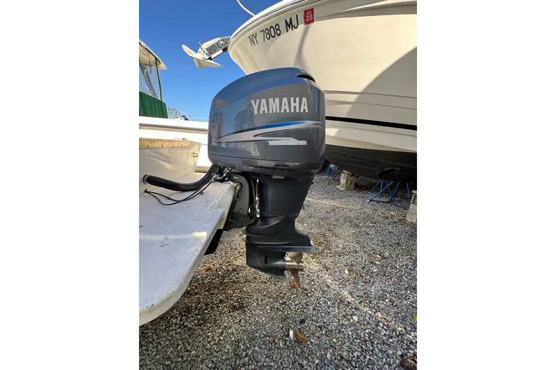 Slide: The Image of Yamaha outboard motor on 1981 Mako 233 Walk Around boat, parked on gravel. - 13