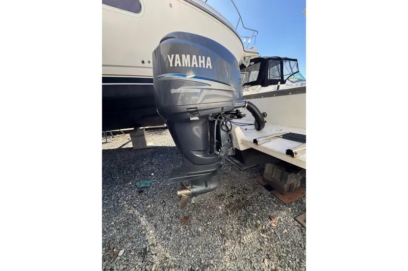 Slide: The Image of Yamaha outboard motor on 1981 Mako 233 Walk Around boat, parked on gravel. - 14