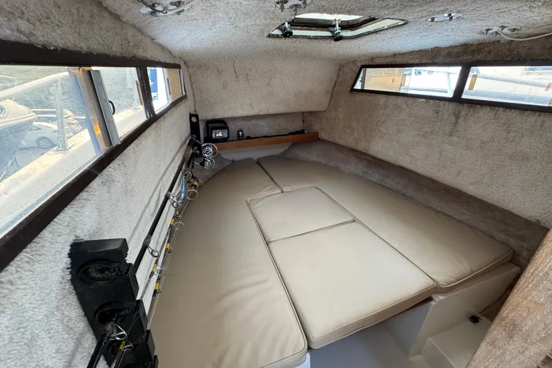 Slide: The Image of Interior cabin of 1981 Mako 233 Walk Around boat with cushioned seating and fishing rods. - 9