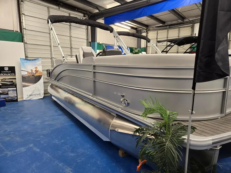 Slide: The Image of 2024 Harris Cruiser 210 pontoon boat on display in a showroom. - 2