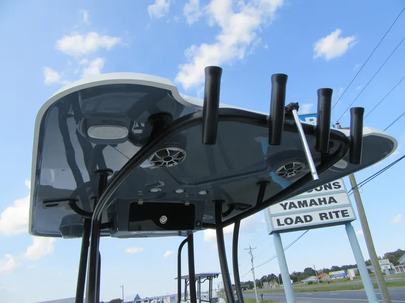 Slide: The Image of 2025 Parker 23 SE CC boat T-top with rod holders against blue sky. - 15