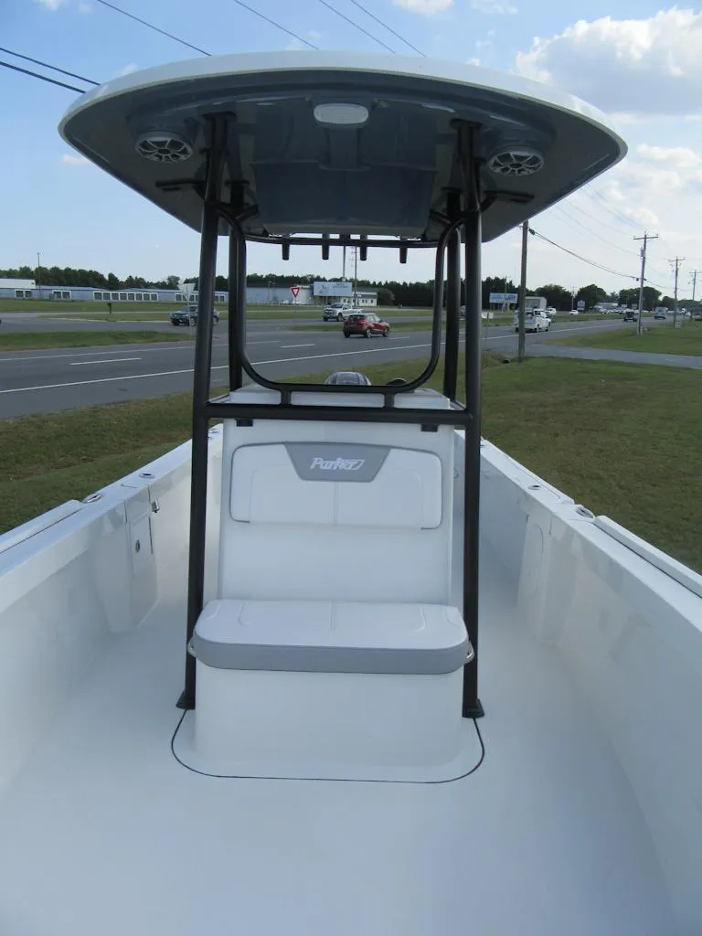 Slide: The Image of 2025 Parker 23 SE CC boat with T-top, parked near a road under a blue sky. - 7