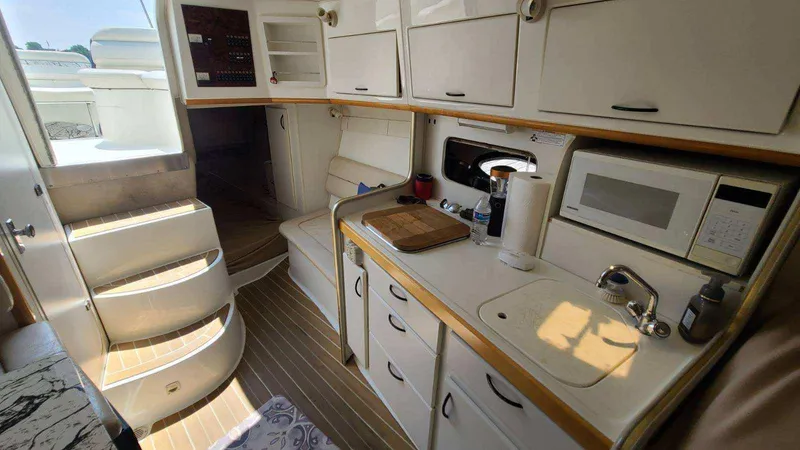 Slide: The Image of Interior of a 1996 Doral 300 SC boat featuring a compact kitchen and seating area. - 3
