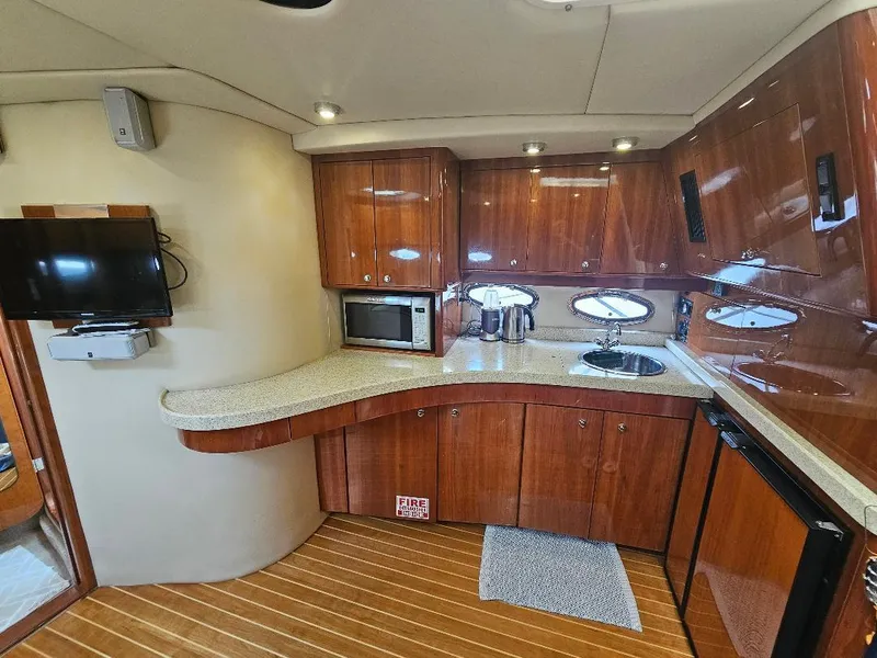 Slide: The Image of 2007 Regal Commodore 4460 yacht kitchen with wooden cabinets, microwave, sink, and TV. - 24