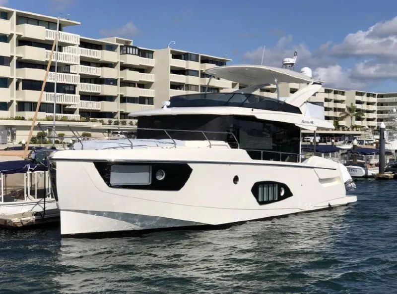 Slide: The Image of 2025 Absolute 48 Navetta yacht docked at a marina with modern buildings in the background. - 18