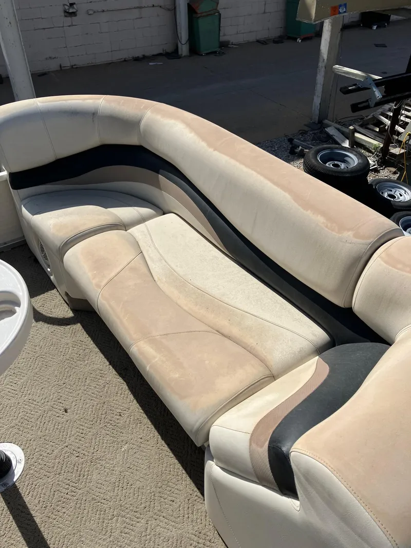 Slide: The Image of 2005 Sun Tracker Party Barge 27 I/O boat seating, beige and black upholstery, outdoor setting. - 28