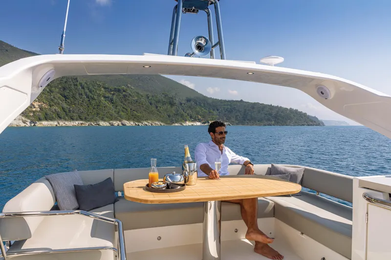 Slide: The Image of Man relaxing on the deck of a 2025 Absolute 47 Fly yacht with scenic ocean view. - 13
